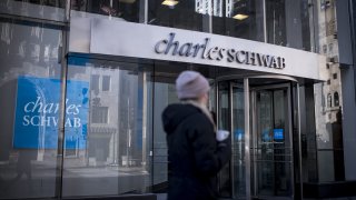 A pedestrian passes in front of a Charles Schwab Corp. bank branch in downtown Chicago, Illinois.
