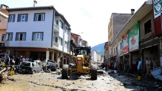 Workers clear the mud from a street in Bozkurt town of Kastamonu province, Turkey