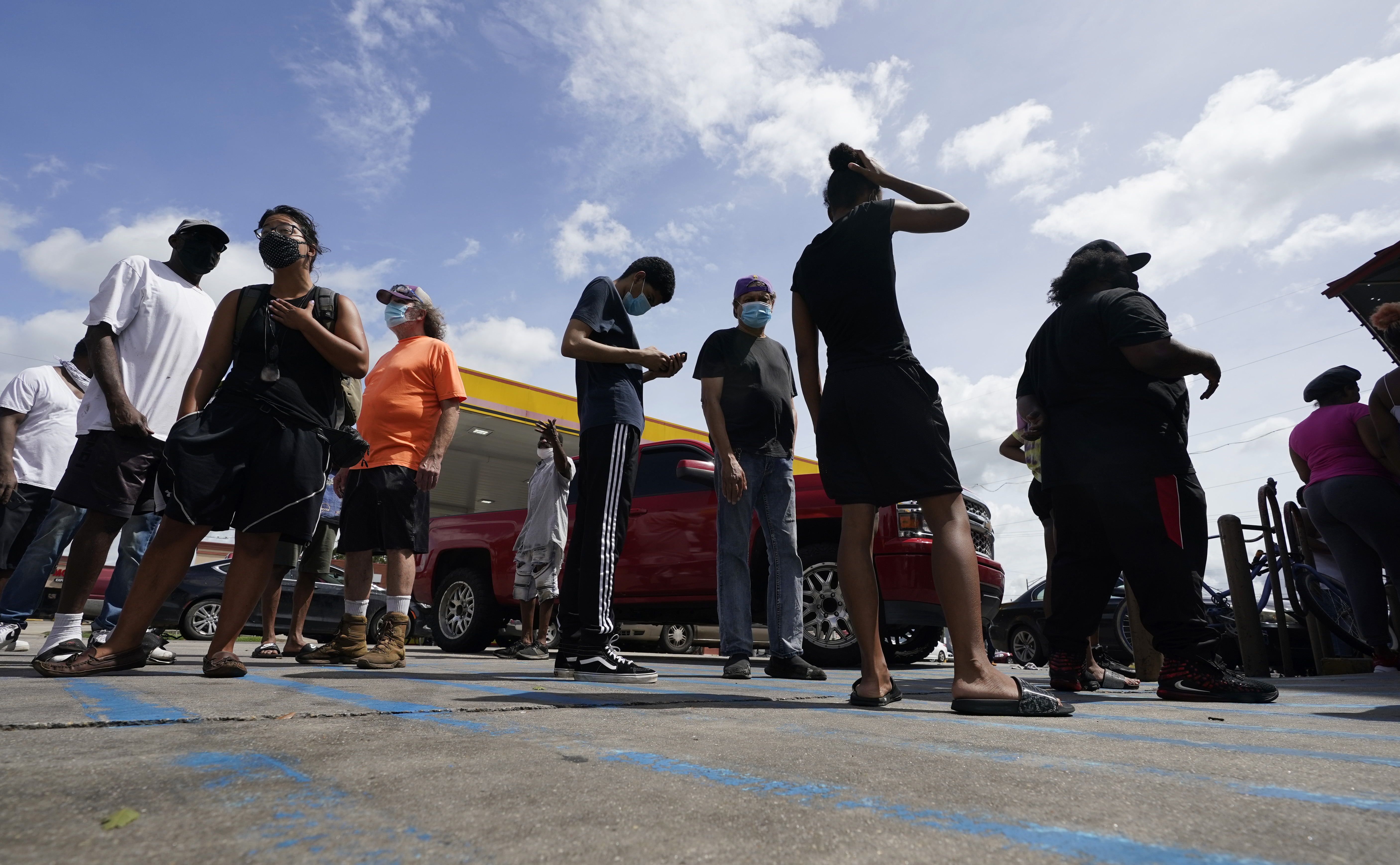 Customers stand in line to enter a convenience store that opened without electricity after the effects of Hurricane Ida knocked out power in the area, Monday, Aug. 30, 2021, in New Orleans, La.