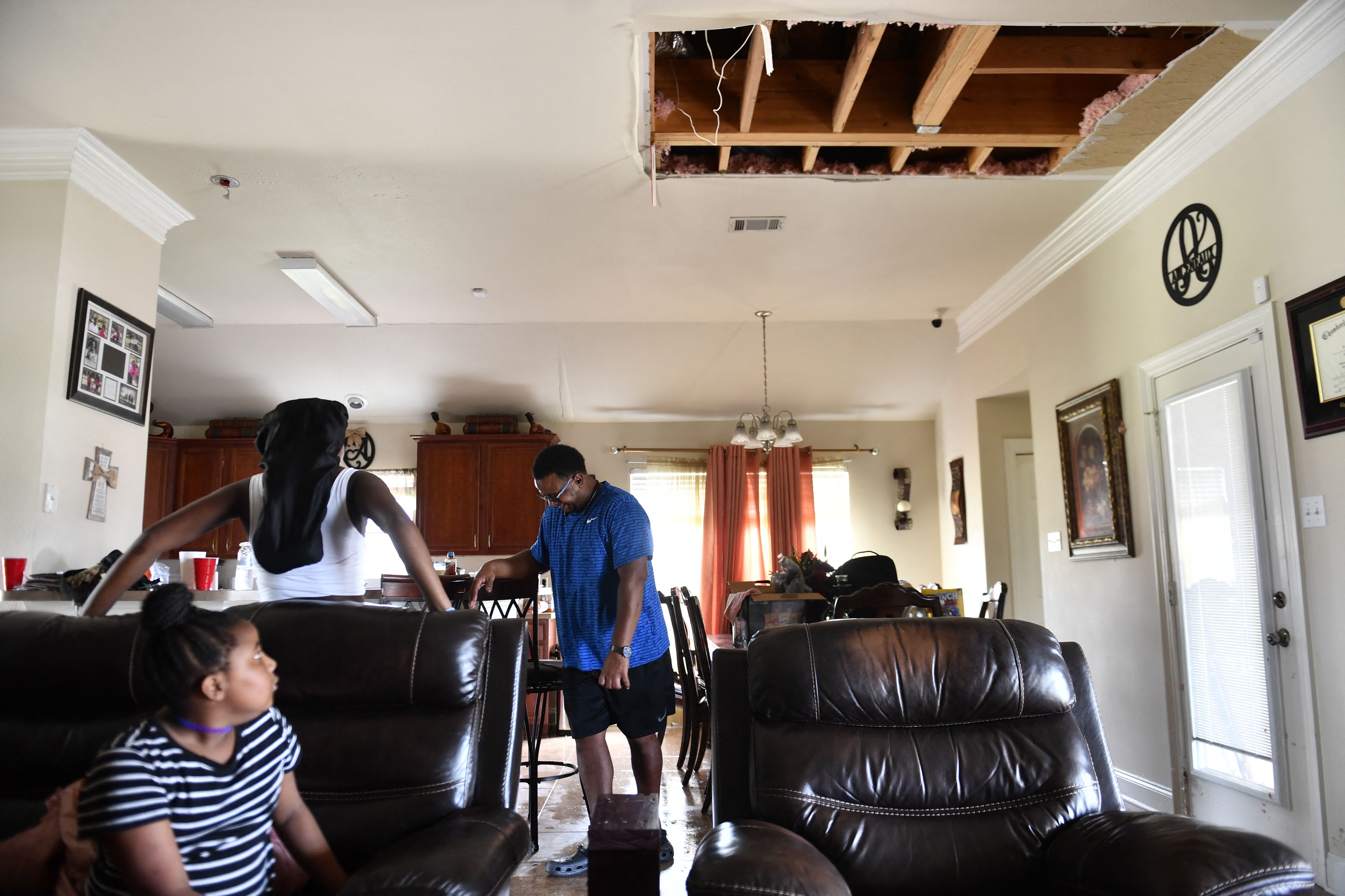 Members of the Arceneaux family look at the damaged ceiling from water in their home in Laplace, Louisiana, on Aug. 30, 2021, after Hurricane Ida made landfall.