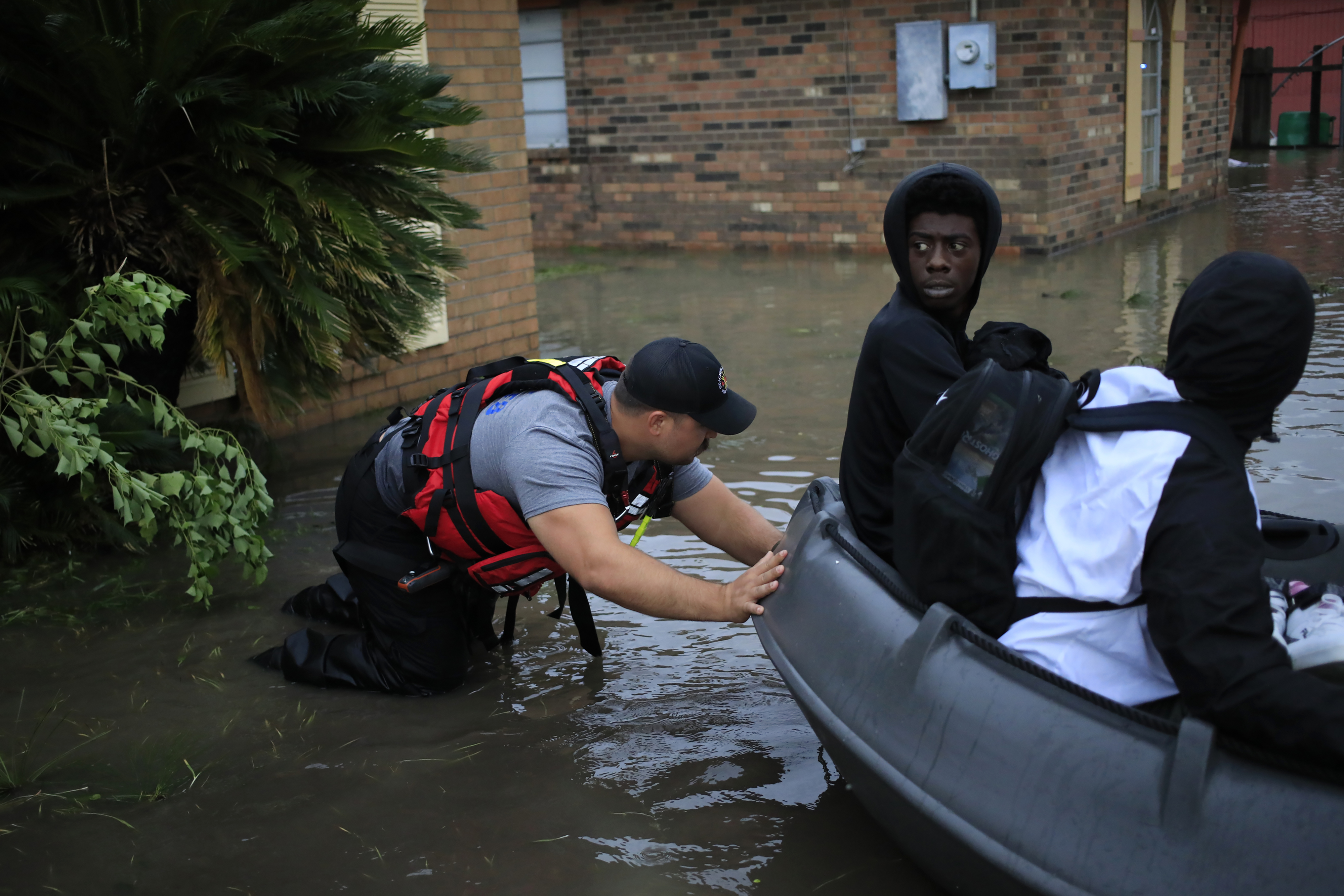 A first responder pushes a rescue boat with residents aboard through floodwaters left behind by Hurricane Ida in LaPlace, Louisiana, U.S., on Monday, Aug. 30, 2021.