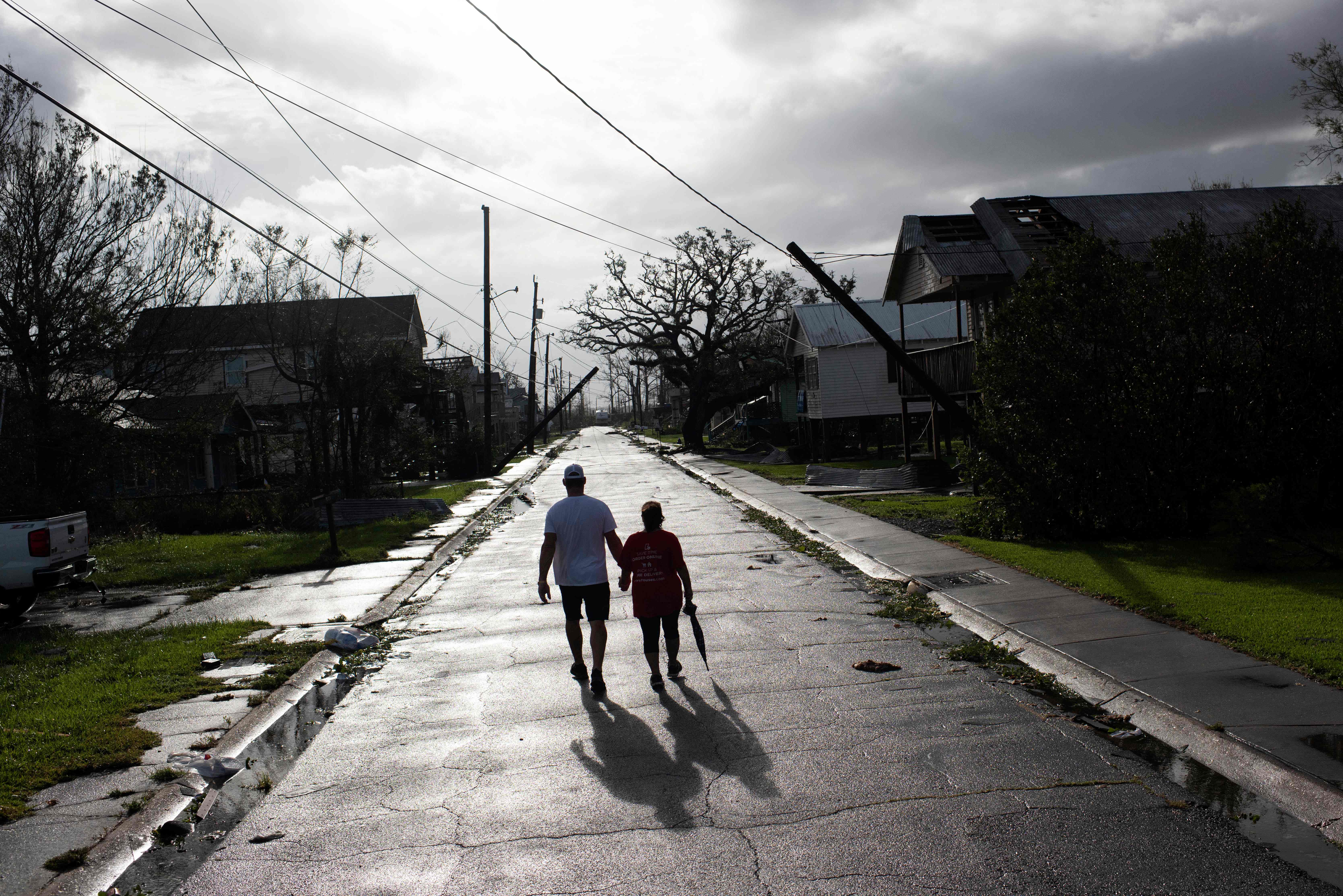 A couple walks down the street while holding hands in Montegut, Louisiana on Aug. 30, 2021, after Hurricane Ida made landfall.