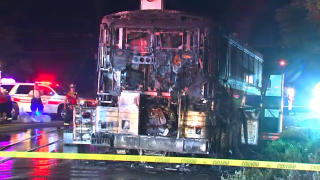 Police tape cordons off a burnt bus after crews extinguished a fire.