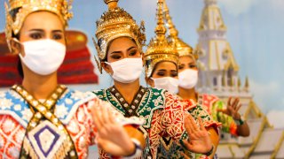 Thai dancers in traditional dresses wear face masks while performing at a temple on May 5, 2020.