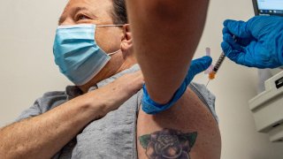 Emergency Medical Technician Ethan Hall gives Mark Turney, 66, a kidney transplant patient, his Pfizer-BioNTech Covid-19 booster shot at Hartford Hospital in Hartford, Connecticut on August 24, 2021.
