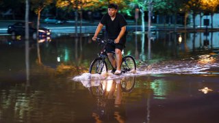 A man rides a bike on the flooded street in the Town of Bound Brook in New Jersey, on September 2, 2021.