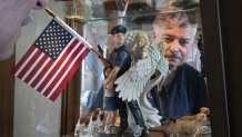 Retired NYPD Officer Mark DeMarco, is seen in a reflection off a display cabinet where he keeps memorabilia from 9/11