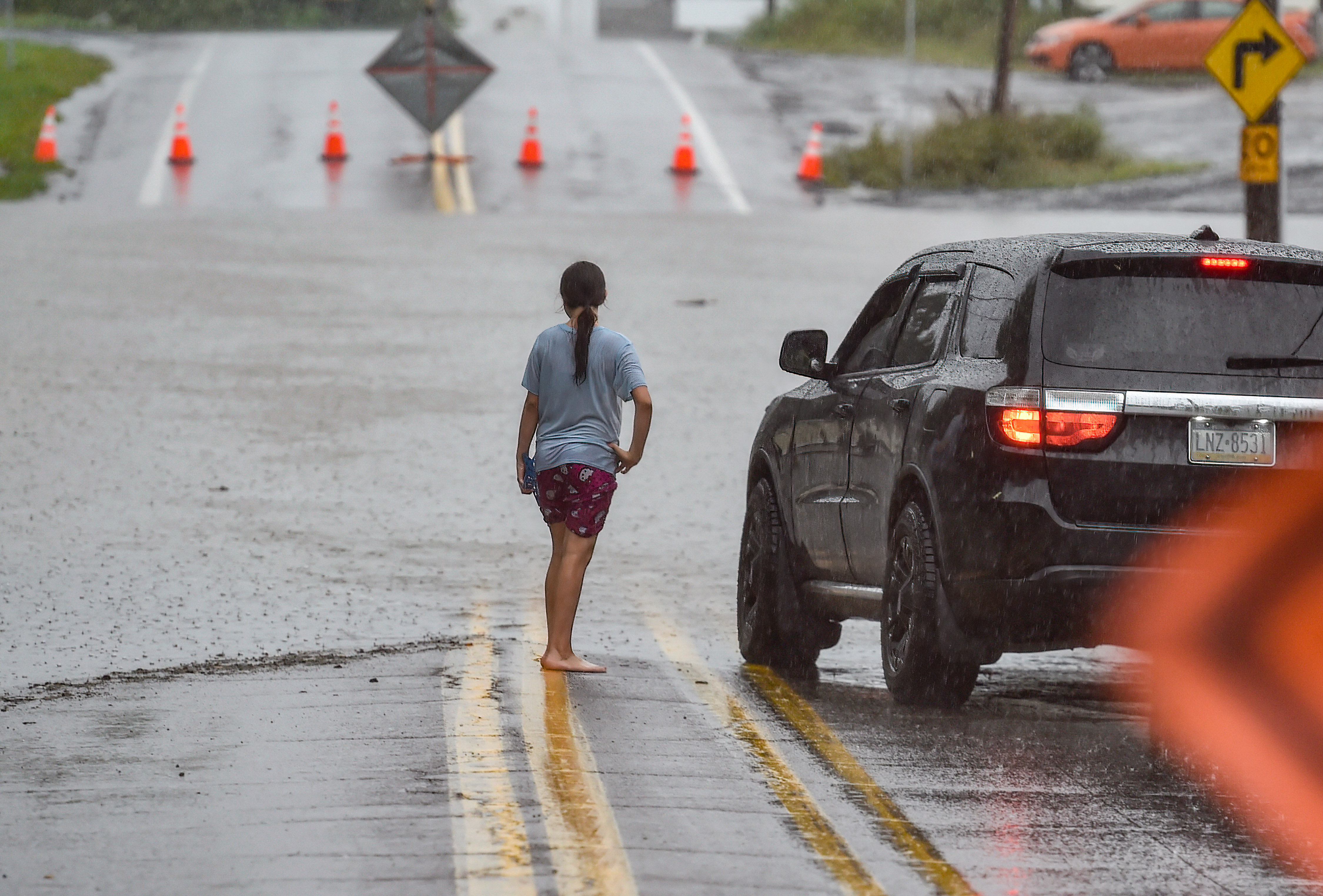 A girl talks to a driver after she walked across a flooded Main street in Wilkes-Barre, Pa. Remnants of Hurricane Ida are moving up the East Coast causing flooding and evacuations in low lying communities.