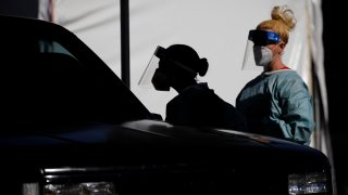 healthcare workers test patients in their cars at a drive-thru coronavirus testing site