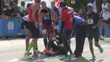 Marathon runner Jamel Melville is helped up by several others near the end of the race course.