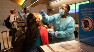 Travelers wearing protective masks receive nasal swabs from nurses at a COVID-19 test site inside Terminal B at Los Angeles International Airport (LAX), on Sunday, Nov. 22, 2020.