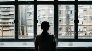 Rear view of woman looking out to city through window