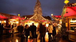 People, many wearing protective face masks, walk past Christmas market stalls near the Cologne Cathedral (Kölner Dom) during the fourth wave of the coronavirus pandemic on November 30, 2021 in Cologne, Germany.