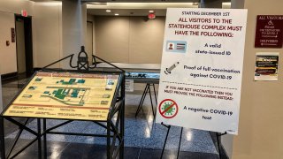 A day after Assembly Republicans successfully defied a mandate to show COVID-19 vaccination proof or a negative test, signs stood around entryways and outside committee rooms at the statehouse showing the mandate remained policy