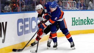 New York Islanders defenseman Robin Salo (2) and New Jersey Devils left wing Jesper Bratt (63) vie for the puck during the third period of an NHL hockey game on Saturday, Dec. 11, 2021, in Elmont, N.Y.