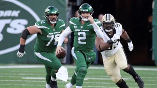 New York Jets quarterback Zach Wilson, center, tries to avoid being tackled during the second half of an NFL football game against the New Orleans Saints