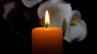 A photo of a candle and orchids for a memorial