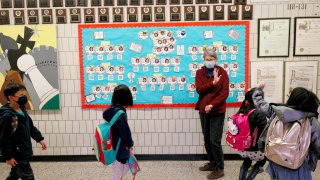 In this photo, paraprofessional Binasa Musovic waves goodbye to students during dismissal at Yung Wing School P.S. 124 on March 25, 2021 in New York City.