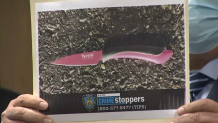 At a press conference, a police officer holds up a photo of the knife allegedly belonging to a man police shot and killed.