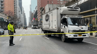 A police officer takes photographs of a box truck involved in a fatal collision on the Upper East Side in New York City.