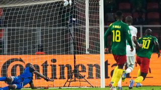 Comoros' goalkeeper Chaker Alhadhur, left, fails to stop a goal shot from Cameroon's Vincent Aboubakar, far right, during the African Cup of Nations 2022 round of 16 soccer match between Cameroon and Comoros at the Olembe stadium in Yaounde, Cameroon, Monday, Jan. 24, 2022.