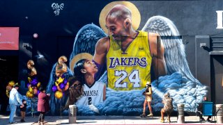 People gather in front of a mural of former Los Angeles Laker Kobe Bryant and his daughter Gianna, both with a set of wings