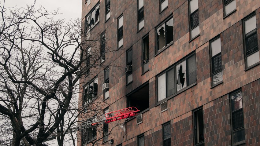 Broken windows and charred bricks mark the exterior of a 19-story residential building