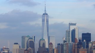 The Empire State building stands next to One World Trade Center seen from the New York harbor