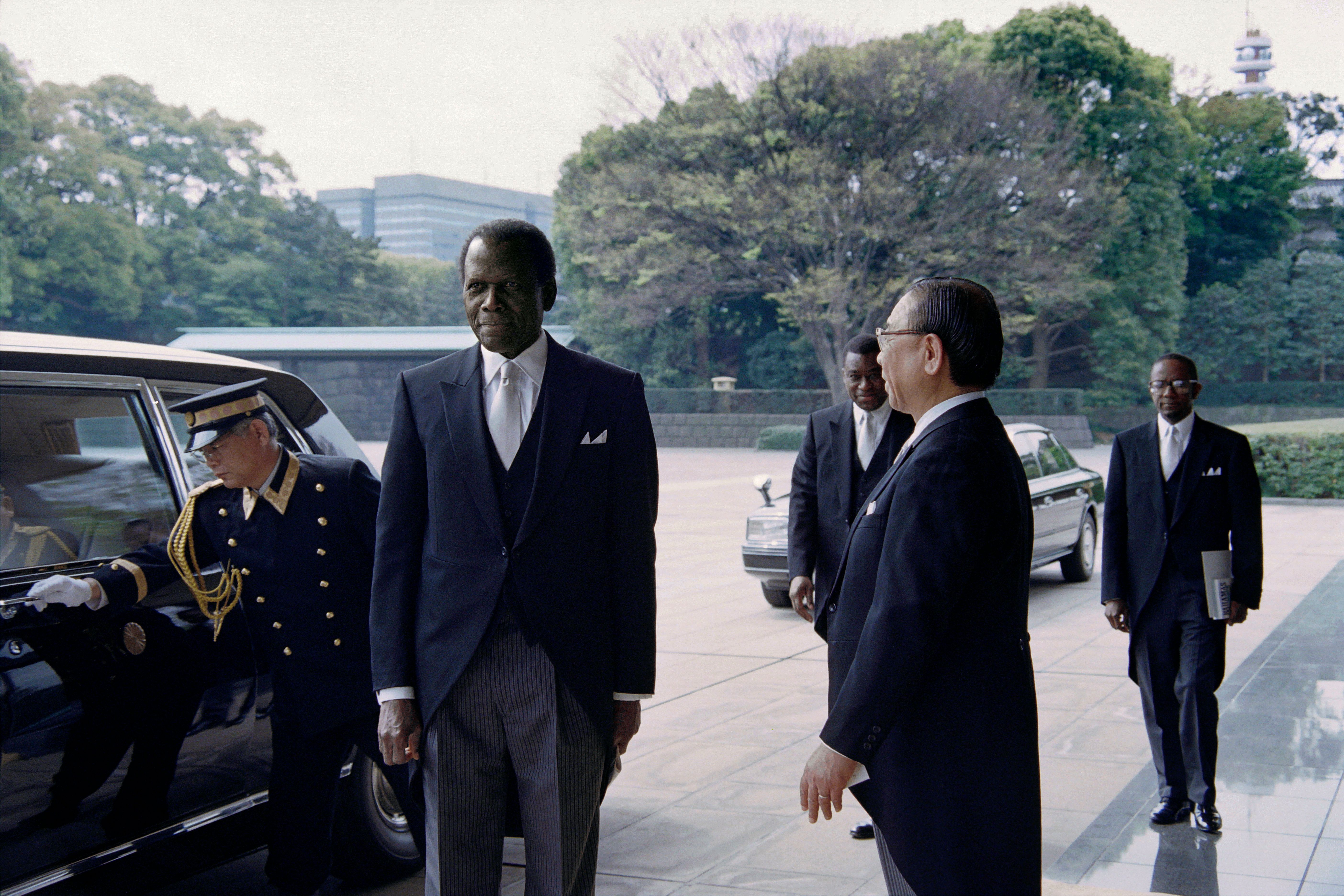 Sidney Poitier, center, is welcomed by the Imperial Palace’s master of ceremony Noriaki Ohwada, right, on April 16, 1997. Poitier presented his credentials to Emperor Akihito to assume his new title of the Bahamas’ Ambassador to Japan.