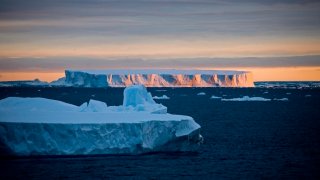 FILE - A view of the sunset over a tabular iceberg