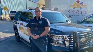 Officer Julio Luis Noriega of the North Bergen Police Department stands next to a police cruiser.