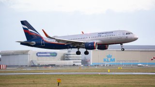 An Aeroflot Russian Airlines Airbus A320 aircraft as seen on final approach flying and landing on the runway at Amsterdam Schiphol Airport with the terminal and the control tower visible, after arriving from Moscow.