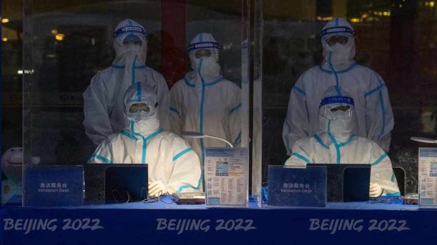 BEIJING, CHINA – JANUARY 24: Officials decked in personal protective equipment wait to validate Olympic accreditation for people arriving at Beijing Capital International Airport on January 24, 2022 in Beijing, China. With just over a week to go until the opening ceremony, final preparations are being made in Beijing ahead of the forthcoming 2022 Winter Olympics. (Photo by Carl Court/Getty Images)