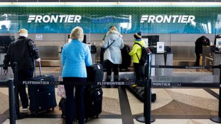 Travelers wait in line at the Frontier Airlines check-in counter at Denver International Airport in Denver, Colorado.