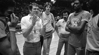 Tom Young, Rutgers University head basketball coach, gestures as he talks to team members following workout at Philadelphia's Spectrum for Saturday's game in the NCAA Basketball Championship, March 27, 1976. Finals are scheduled for Saturday and Monday. Players are unidentified.