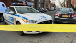 A police cruiser is parked behind caution tape at the scene of a fatal Bronx shooting.