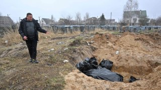 A man gestures at a mass grave in the town of Bucha, northwest of the Ukrainian capital Kyiv on April 3, 2022.