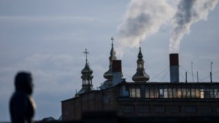 FILE - A woman walks with a power plant in the background, in Vinnytsia, Ukraine, March 16, 2022. Ukrainian officials say Russian military hackers tried to knock out power to millions of Ukrainians last week in a long-planned attack but were foiled. However, the Ukrainians say the Russian hackers succeeded in penetrating and disrupting the industrial control system of one power station. The Ukrainians says the defenders were able to thwart any power loss.