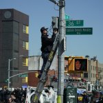 A member of the NYPD retrieves a security camera near a subway station in New York City on April 12, 2022, after at least 16 people were injured during a rush-hour shooting in the Brooklyn neighborhood of Sunset Park.