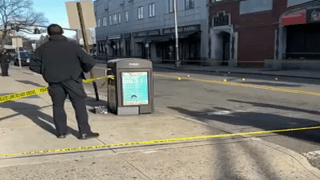 Police officer stands behind caution tape at scene of double stabbing