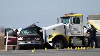 Investigators look over the scene of a crash between an SUV and a semi-truck full of gravel near Holtville, California on March 2, 2021.