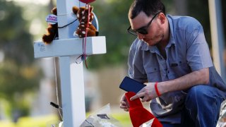 A man kneels at a memorial in Town Square in front of the county courthouse, for victims of the Robb Elementary school shooting, three days after a gunman killed nineteen children and two adults, in Uvalde, Texas, U.S. May 27, 2022. 