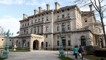 Visitors walk toward an entrance to The Breakers mansion in Newport, R.I.