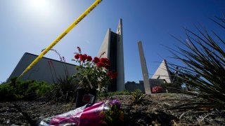 Flowers sit outside crime scene tape at Geneva Presbyterian Church on Tuesday, May 17, 2022, in Laguna Woods, Calif.