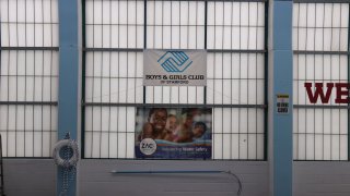 A Boys & Girls Club poster hangs on top of a ZAC Foundation poster at an indoor pool