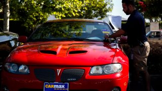 An employee places a pending sale sticker on a used Pontiac GTO vehicle outside of a CarMax Inc. dealership in Burbank, California, U.S., on Tuesday, June 17, 2014.