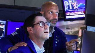 Traders react on the floor of the New York Stock Exchange (NYSE) as a screen shows Federal Reserve Board Chairman Jerome Powell during a news conference following a Fed rate announcement, in New York City, July 27, 2022.