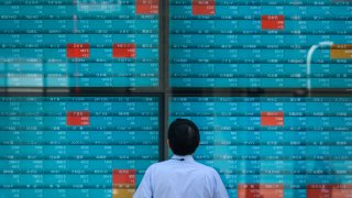 A man looks at an electronic quotation board displaying stock prices on the Tokyo Stock Exchange in Tokyo on August 2, 2022.