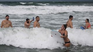 Members of the slow-pitch softball team Siteman/Pure play in the surf on Cocoa Beach on September 28, 2022, as the eastern coast of central Florida braces for Hurricane Ian.