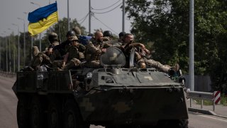 Ukrainian servicemen ride atop of an armored vehicle